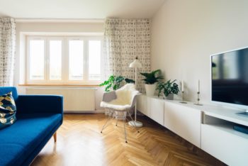 Herringbone pattern hardwood floors apartment blue couch window
